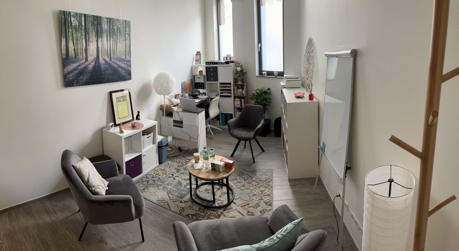 Le cabinet : fauteuils, table basse et bureau dans une pièce lumineuse